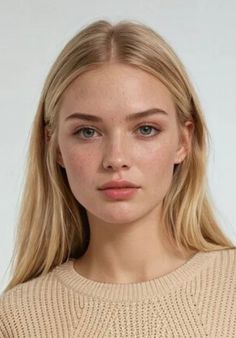 Close-up portrait of a woman with blonde hair and freckles wearing a beige sweater