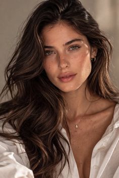Woman with long brown hair and freckles wearing a white shirt and necklace