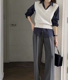 Person in a sleeveless sweater over a collared shirt and wide leg pants