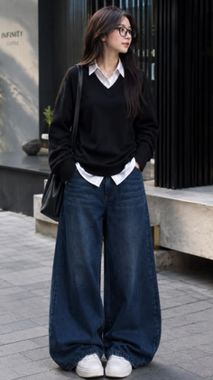Woman in a black sweater and wide leg jeans standing outdoors