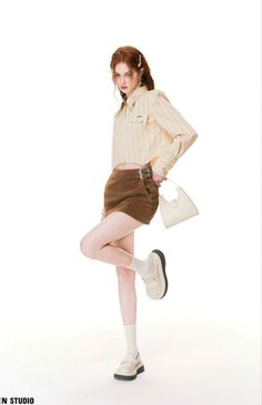 Woman with red hair in a cropped shirt and brown skirt posing in a studio