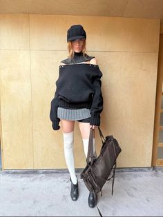Woman in a black off-shoulder sweater, short skirt, and white thigh-highs holding a bag