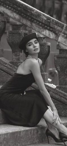 Woman in a black dress and beret with a veil, sitting on stone steps