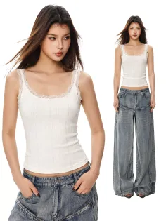Woman in a white lace-trim tank top and baggy jeans posing in a studio