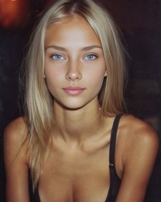Blonde woman with blue eyes wearing a black bra, upper body portrait