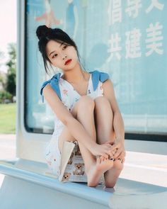 Woman in a white dress with blue bows sitting barefoot outdoors