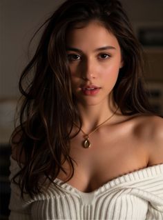Woman with long brown hair wearing an off-shoulder sweater and gold necklace