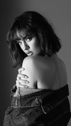 Woman with short hair and a denim jacket draped over her shoulders, looking over her shoulder