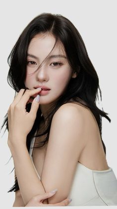 Woman with long black hair in a white top, biting her finger