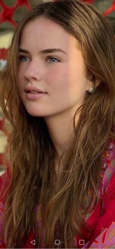 Woman with long brown hair and blue eyes wearing a red top