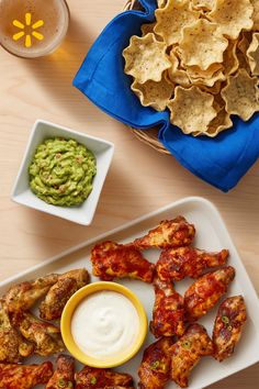 Chicken wings, guacamole, tortilla chips, and beer on a wooden table