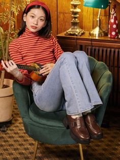 Woman in a red striped turtleneck and jeans sitting in a chair with a ukulele