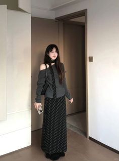 Woman with long hair wearing an off-shoulder top and polka dot skirt indoors