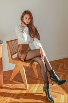 Woman with long hair in a white blouse and mini skirt sitting on a chair