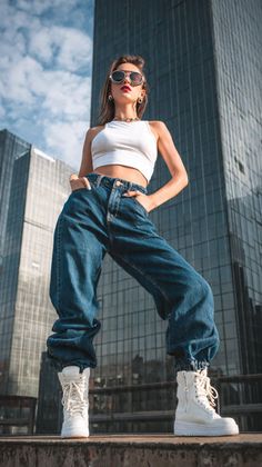 Woman in a white crop top and baggy jeans posing in a cityscape