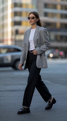 Woman in a gray blazer and black jeans walking on a street