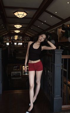 Woman in red shorts and a black halter top posing in a dimly lit bar