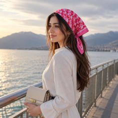 Woman in a white dress and pink headscarf by the sea at golden hour