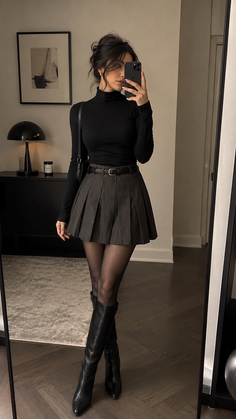 Woman in a black turtleneck and pleated skirt taking a mirror selfie