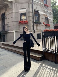 Woman in a black off-shoulder top and flare pants on a city street