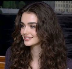 Woman with long wavy dark hair smiling outdoors
