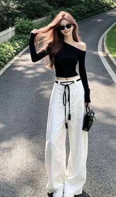 Woman in a black off-shoulder top and white pants on an outdoor path