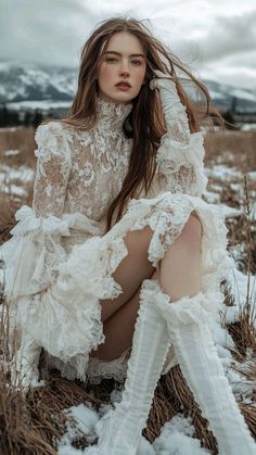 Woman in a white lace dress and long gloves sitting in a snowy field