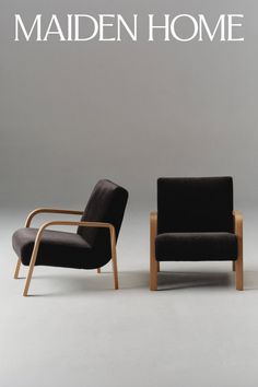 Two armchairs with wooden frames and dark upholstery in a studio setting