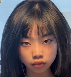 Close up portrait of a young person with long black hair and bangs
