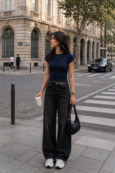 Woman in a navy crop top and wide leg jeans on a city street