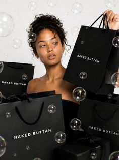 Woman with curly hair in an updo surrounded by black shopping bags and bubbles