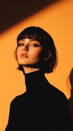 Woman with short hair in a black turtleneck with dramatic lighting