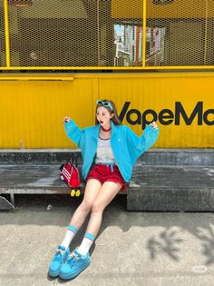 Woman in red shorts and a blue jacket sitting on a bench outdoors