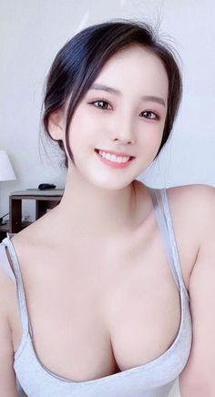 Woman with black hair and a gray top smiling at the camera indoors