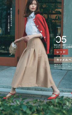 Woman in a red cardigan and pleated skirt walking outdoors