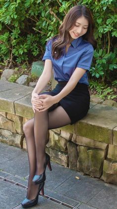 Woman in a blue shirt and black skirt sitting outdoors