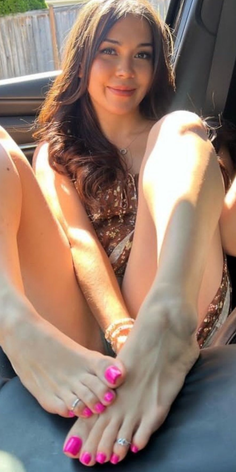 Woman in a floral dress with pink nail polish and toe rings in a car