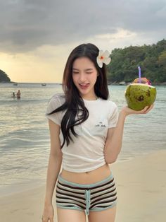 Woman with long hair holding a coconut drink on a beach