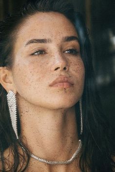 Woman with freckles wearing long earrings and a necklace