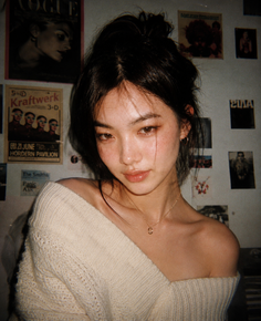 Woman with a messy bun wearing an off-shoulder sweater indoors
