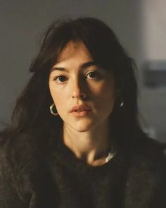 Woman with long dark hair and hoop earrings in dramatic lighting