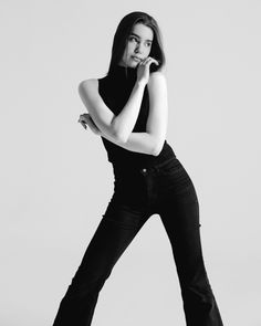 Woman in a black turtleneck and jeans posing in a studio