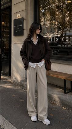 Woman in a brown jacket and wide leg pants standing outside a coffee shop