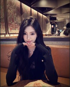 Woman with long black hair wearing a black top in a restaurant