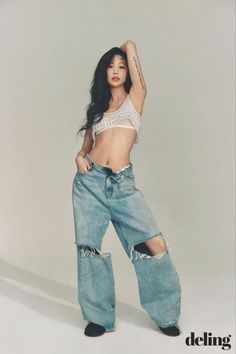 Woman with long dark hair wearing a crop top and ripped jeans in a studio