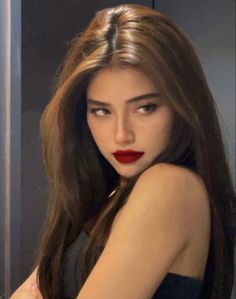 Woman with long brown hair and red lipstick looking over her shoulder