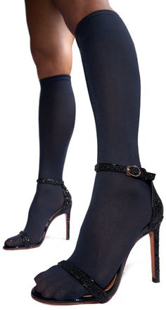 Legs in black stockings and glitter high heels against a white background