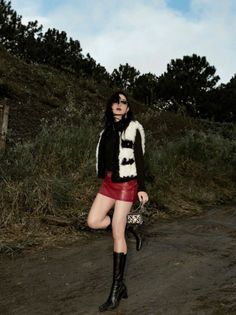 Woman in a red leather skirt and fur vest posing outdoors