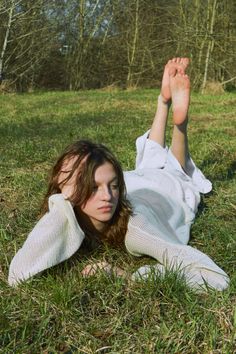 Woman with long hair lying on green grass with her feet up