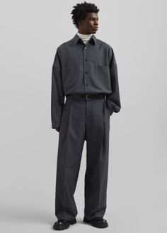 Man in a dark gray shirt and wide leg pants with a white turtleneck